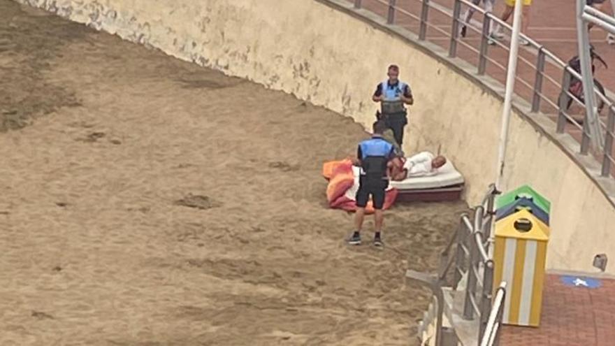 Una habitación con vistas a Las Canteras: dos personas montan una cama sobre la arena