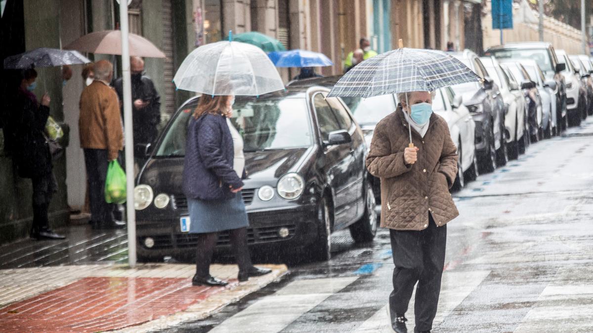 Peatones protegiéndose de la lluvia en Alicante