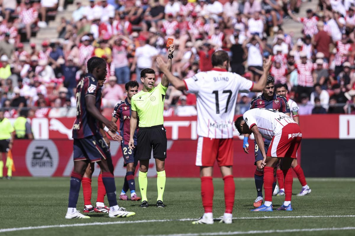 Vitor Reis, agachado, no ve la tarjeta roja que le muestra el árbitro Alejandro Quintero González tras cometer una falta al borde del área.