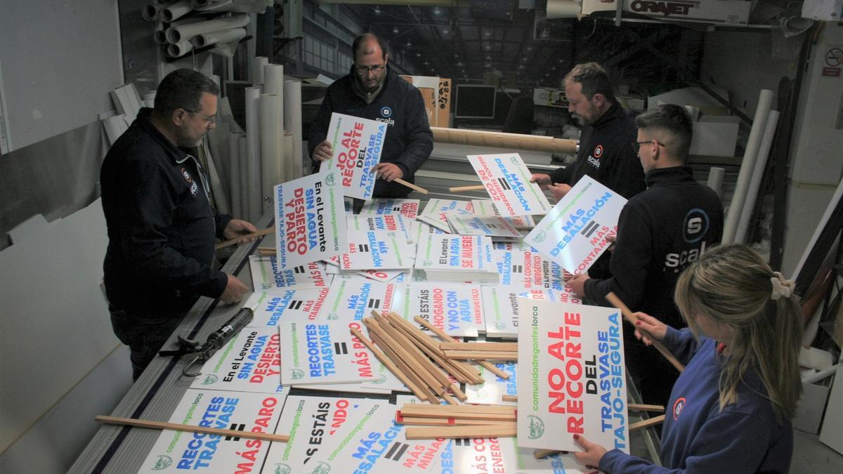 Trabajadores de la imprenta Scala de Lorca, anoche, preparando carteles para la manifestación de los regantes en Madrid.