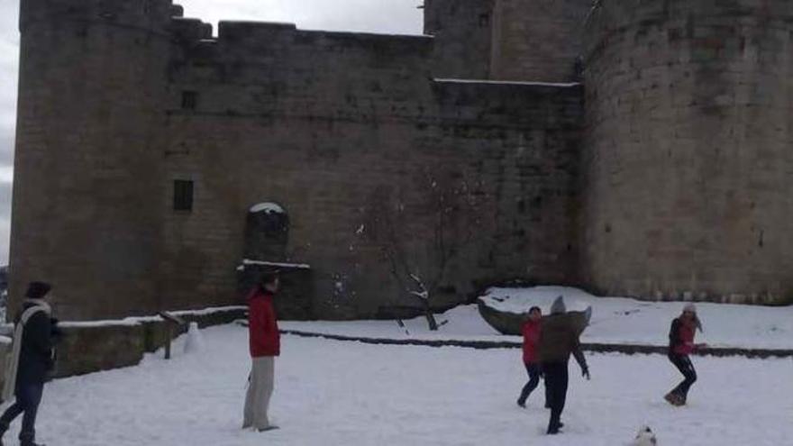 Un grupo de personas juega con la nieve frente al castillo de Puebla de Sanabria. Foto