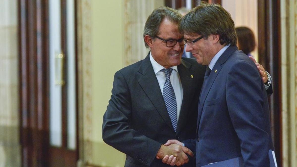 El presidente de la Generalitat, Carles Puigdemont, con su antecesor en el cargo, Artur Mas, antes de su discurso en el Parlament, este miércoles por la tarde.