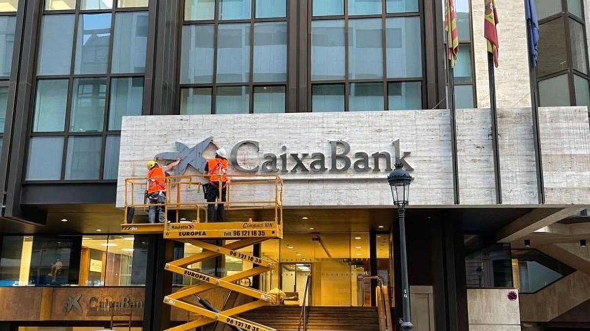 Operaris col·loquen el logotip de CaixaBank a l’edifici que acollia la seu de Bankia a València. | EUROPA PRESS