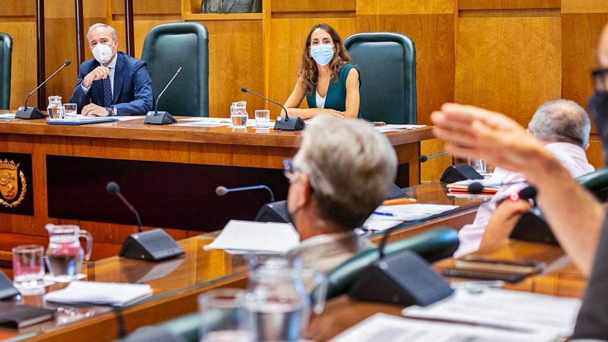 Azcón, de fondo, junto a la portavoz popular, María Navarro, mirando a la bancada de su izquierda durante el pleno extraordinario.