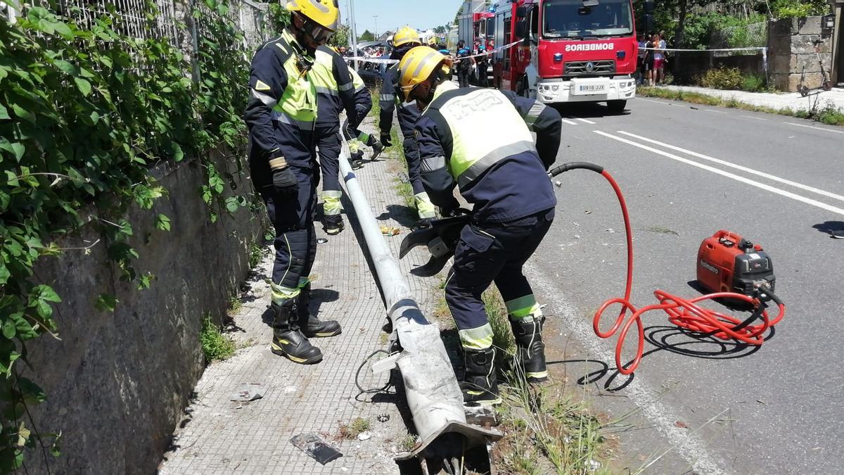 Los bomberos retiran la farola derribada por este vehículo.