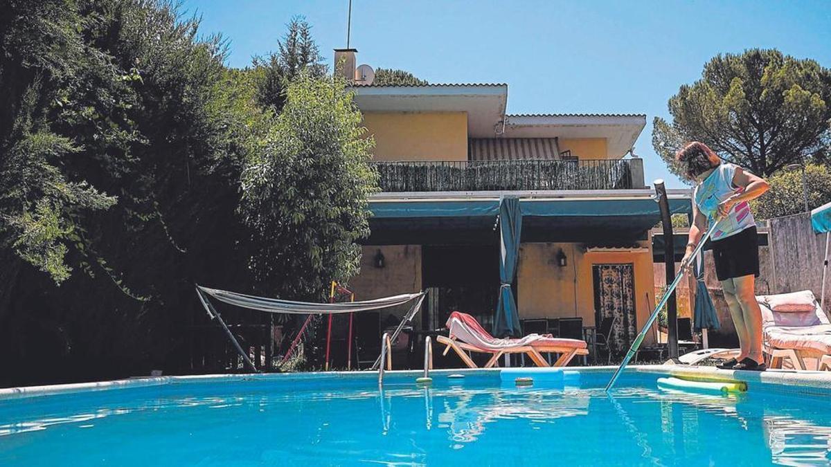 Ana Sánchez limpia la piscina de su casa, en la que vive durante el verano, en la barriada de Trassierra.