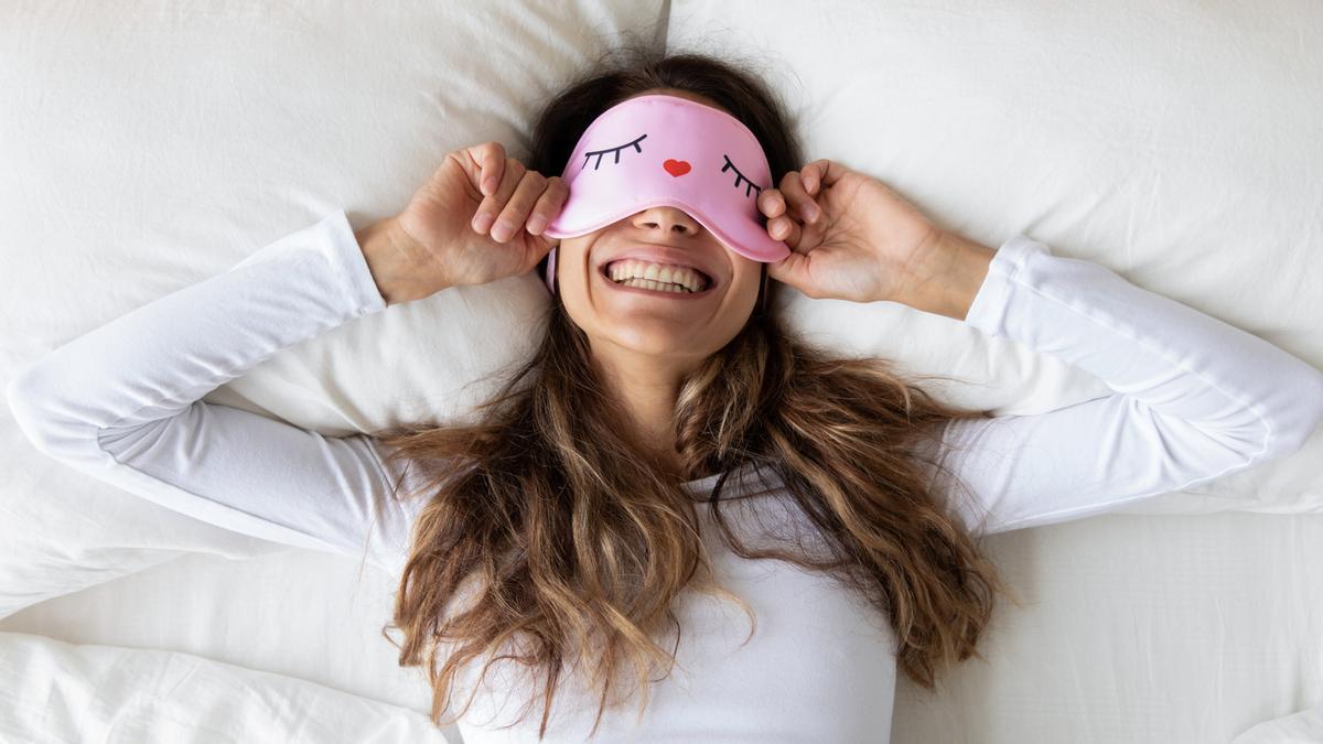 Chica en la cama con antifaz para dormir