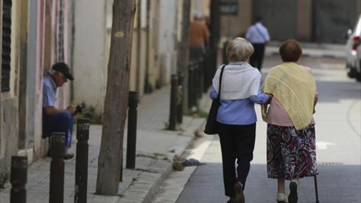 Dos mujeres mayores pasean por la calle.