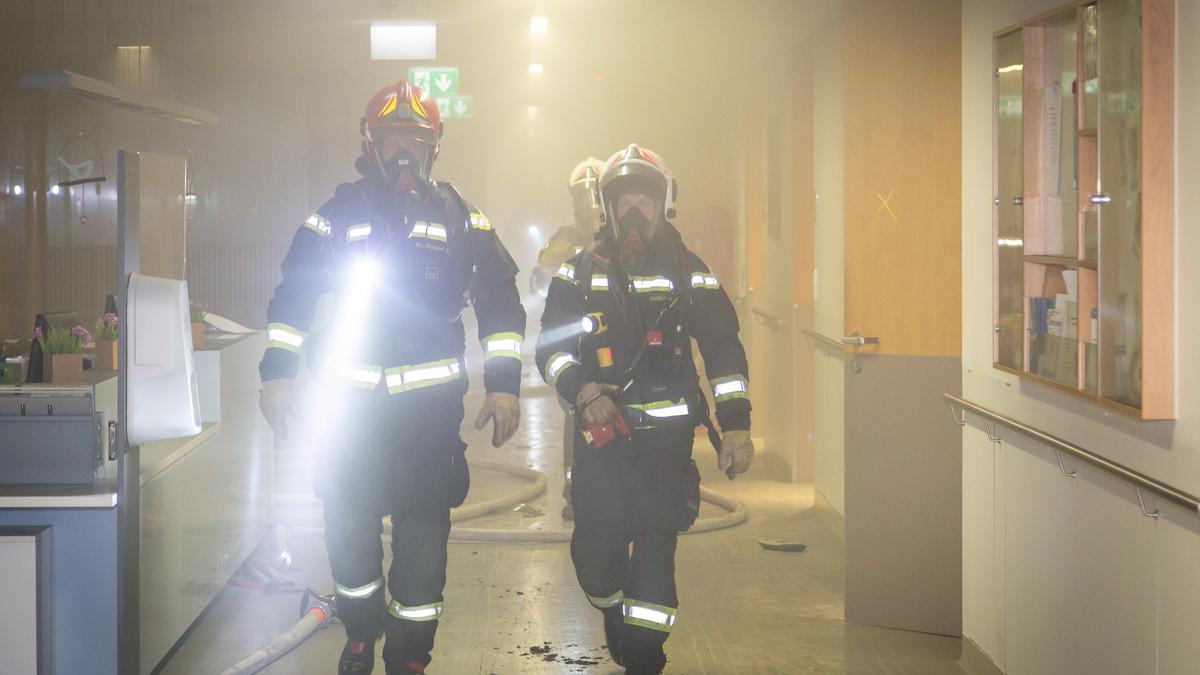 Tres bomberos inspeccionan el hospital tras apagar el incendio.