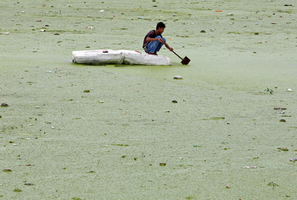 Un chico navega por el río con una improvisada balsa.