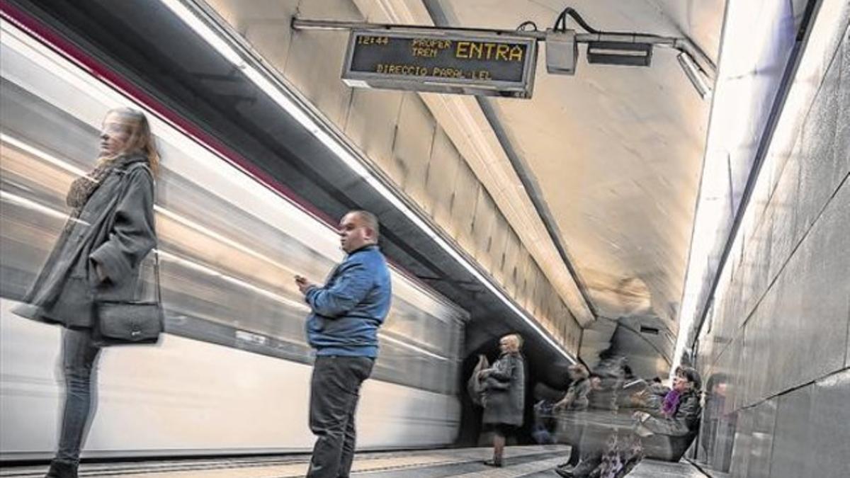 Usuarios del metro de Barcelona junto a un cartel luminoso, la semana pasada.