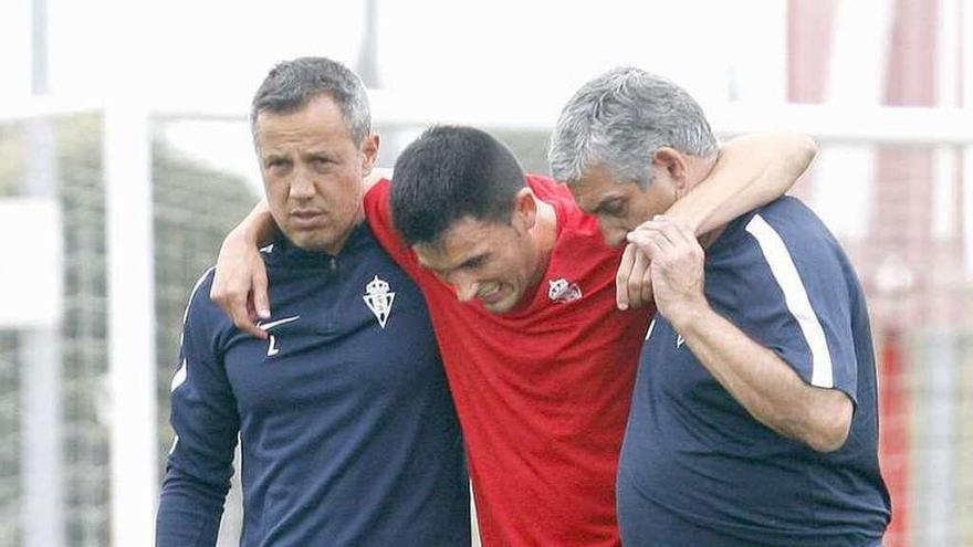 Diego Lobelle y Juan Cachero ayudan a Isma López a abandonar el campo de entrenamiento.