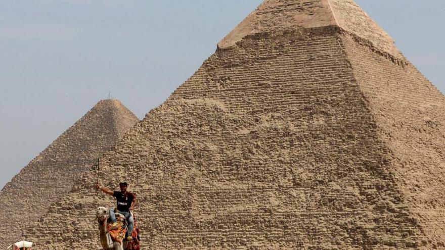 Un hombre monta en camello frente a la Gran Pirámide de Keops.