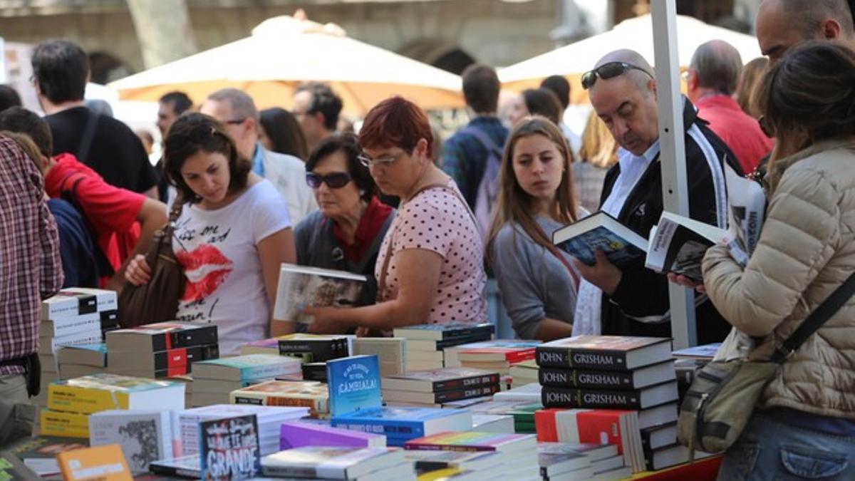 Lectores buscando nuevas lecturas en algunos de los puestos que inundan Barcelona en la festividad de Sant Jordi.
