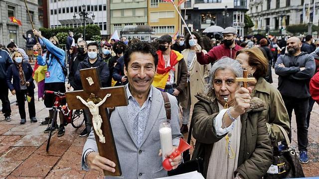 Juan Carlos, con el crucifijo, y otra participante en la protesta contra Abramovic, con manifestantes republicanos detrás, ayer, en la plaza de la Escandalera. | Julián Rus