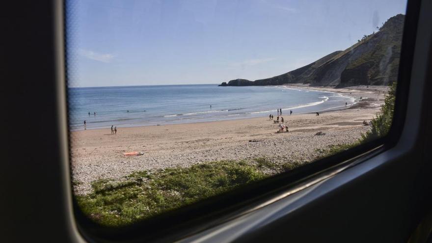 Un tren, pasando por la costa asturiana, por la playa de San Antolín en Llanes.