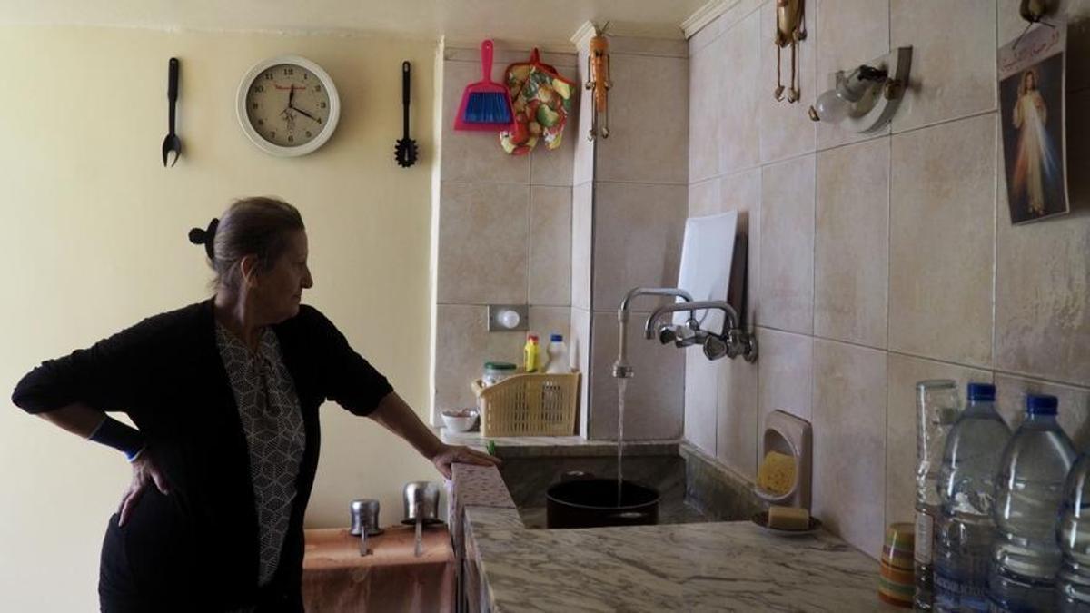 Umm Rafi, libanesa armenia de 77 años, llena de agua una olla para calentarla y poder ducharse.