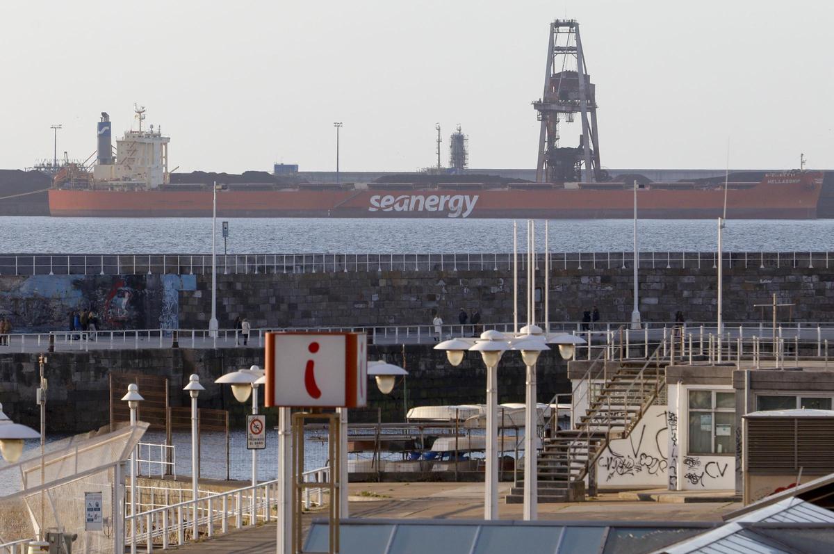 En primer término, espacios del Puerto Deportivo de Gijón, con un buque en la terminal de minerales de El Musel, al fondo.