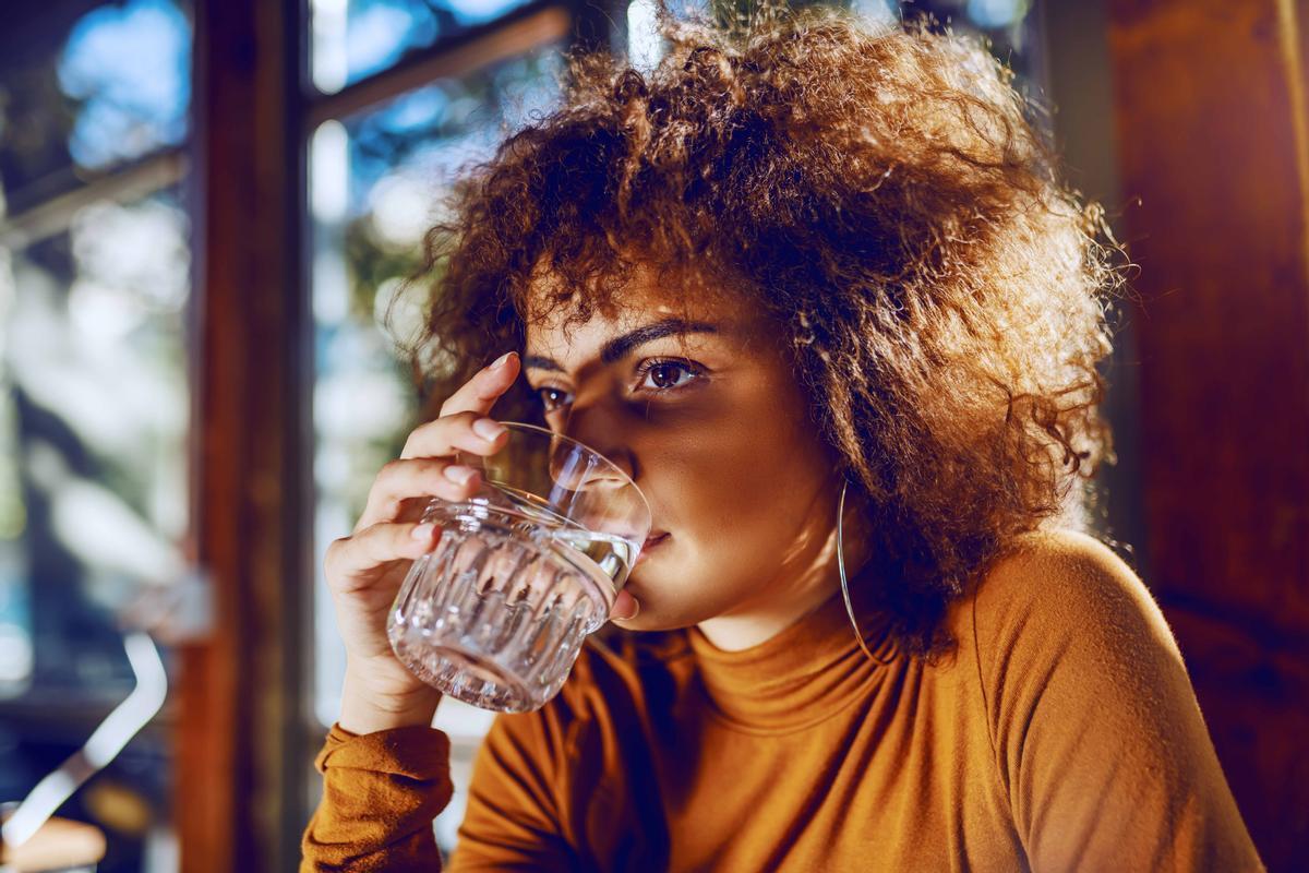 Una mujer bebe un vaso de agua.