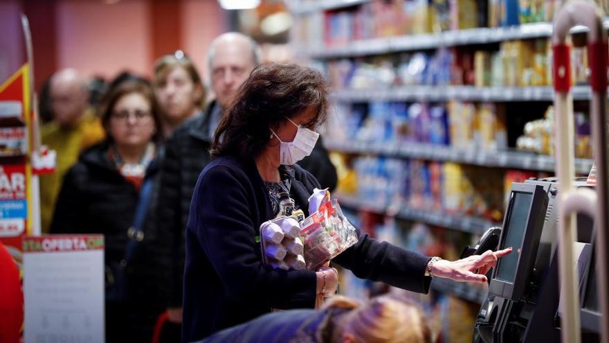 Una mujer con mascarilla realiza la compra en un supermercado.