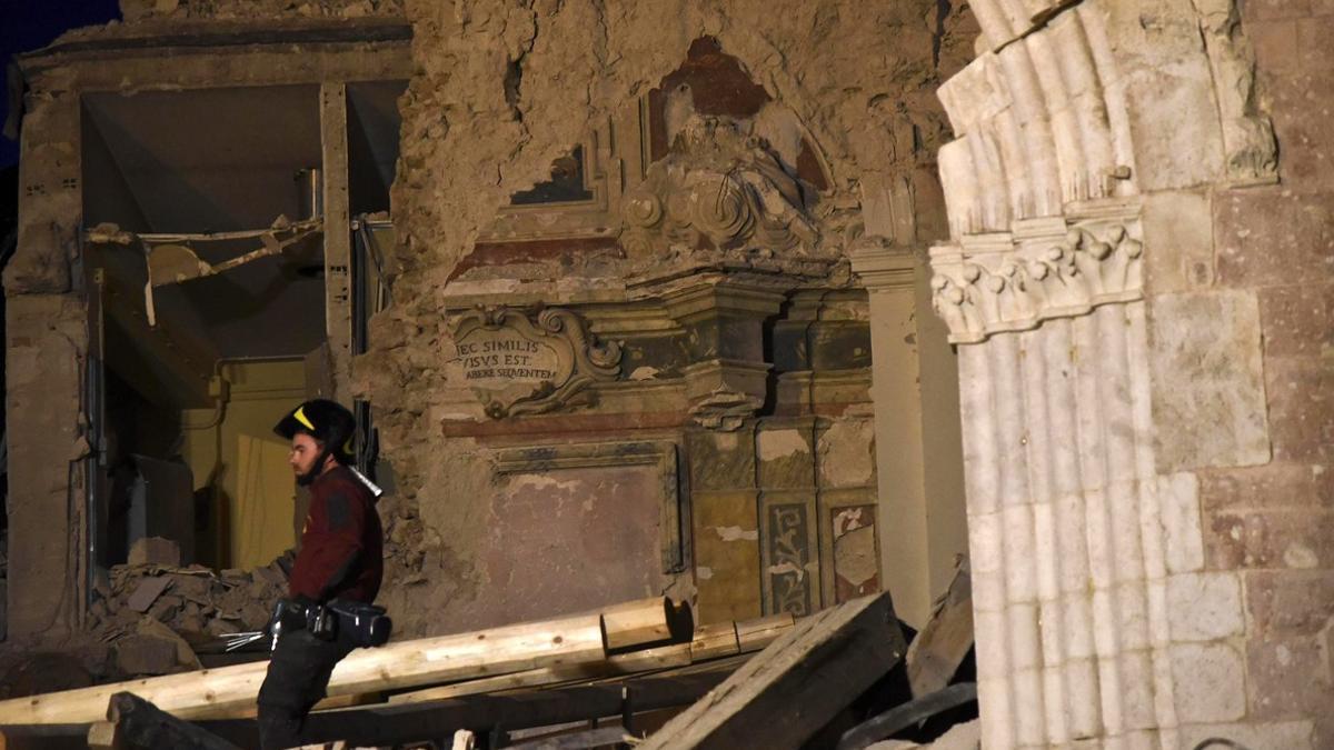 Un bombero trata de recuperar objetos de la basílica de San Benedetto, en Norcia, dañada por los terremotos.