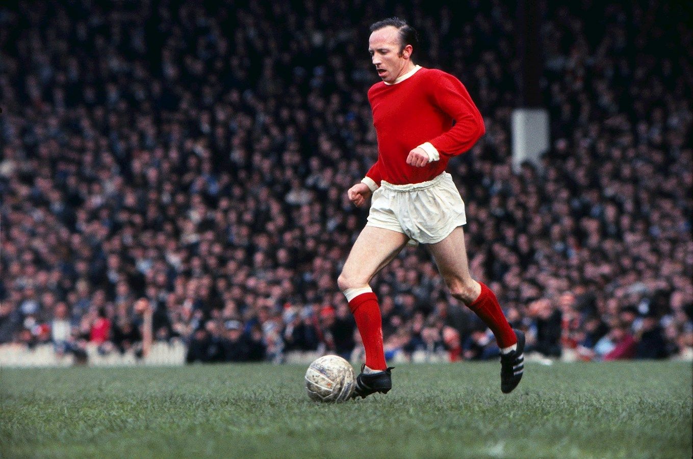 Stiles conduce un balón en un partido con el United