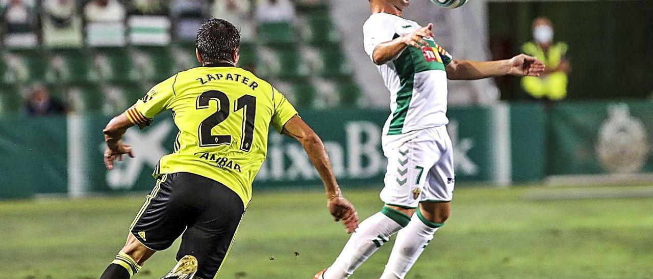 El delantero franjiverde Nino controla en el partido de ida en el Martínez Valero ante la presión del zaragocista Zapater.