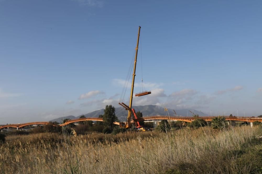 La instalación del último tramo del puente de madera sobre el río Guadalhorce ha comenzado este martes.