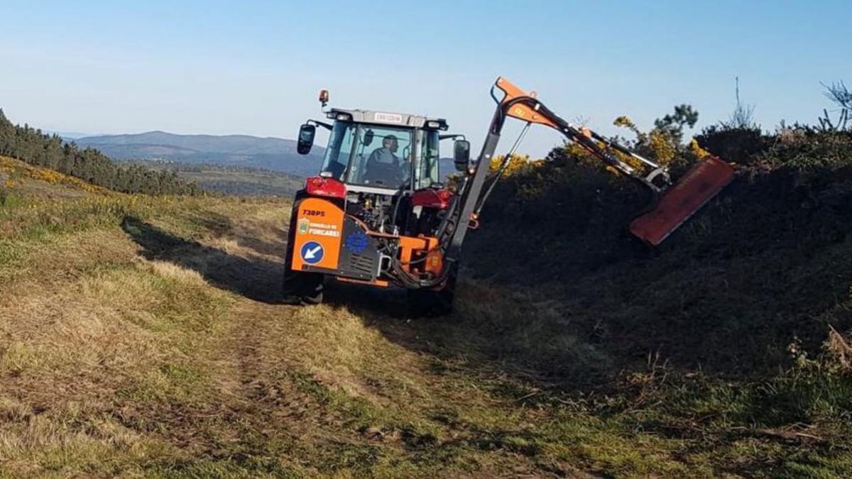 Un tractor trabaja en la limpieza de una parcela rural.