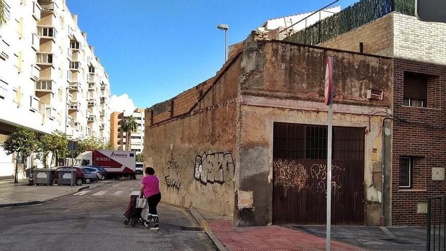 La foto fue tomada el pasado 17 de diciembre. Una mujer sale a la calzada de la calle Edward Elgar con su carrito de la compra, ante la presencia de un antiguo almacén o taller de cerrajería abandonado, que además de cortar la acera estrangula la calle, que en este tramo pasa de dos direcciones a una.