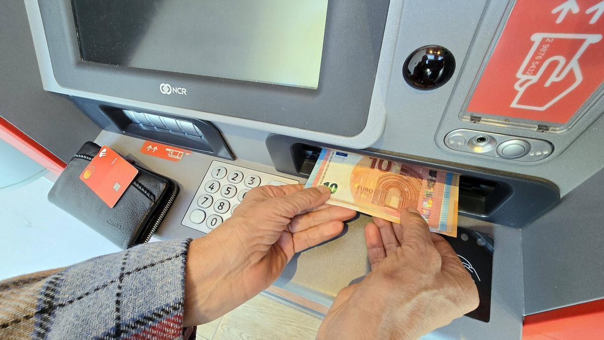 Una persona retira diners en efectiu d'un caixer automàtic.