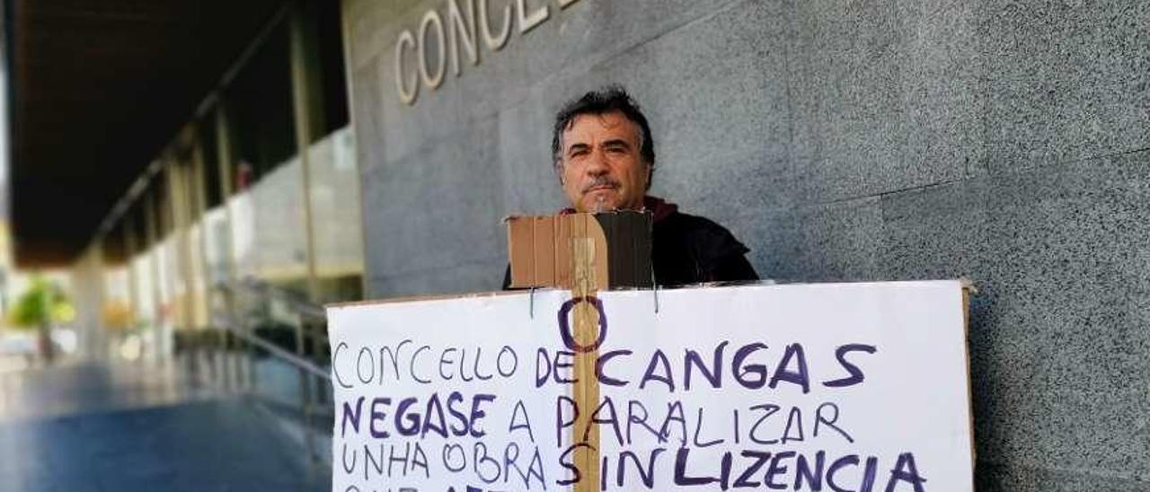 Protesta bajo la lluvia otoñal. Esperemos que este hombre que protesta delante del Concello se resguarde bien de la lluvia. Para no coger de esos catarros que después no se sueltan en todo el año. Este vecino protesta porque el Concello no paraliza una obra que no tiene licencia y que afecta a su propiedad. Lo explica bien en el letrero.  Gonzalo Núñez