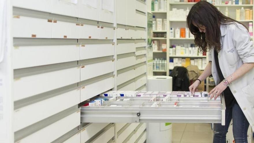 Una farmacéutica busca un medicamento en el almacén de una farmacia
