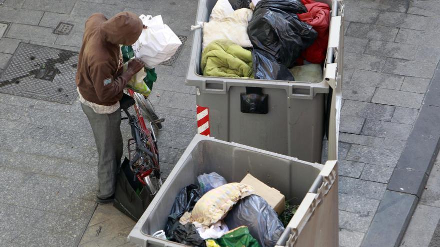 Hombre rebusca en un contenedor de basura en València