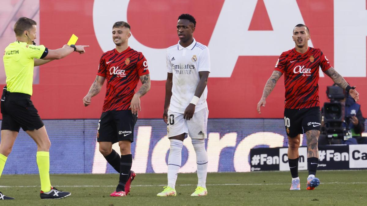 El árbitro muestra tarjeta amarilla a Maffeo en presencia de Vinicius.