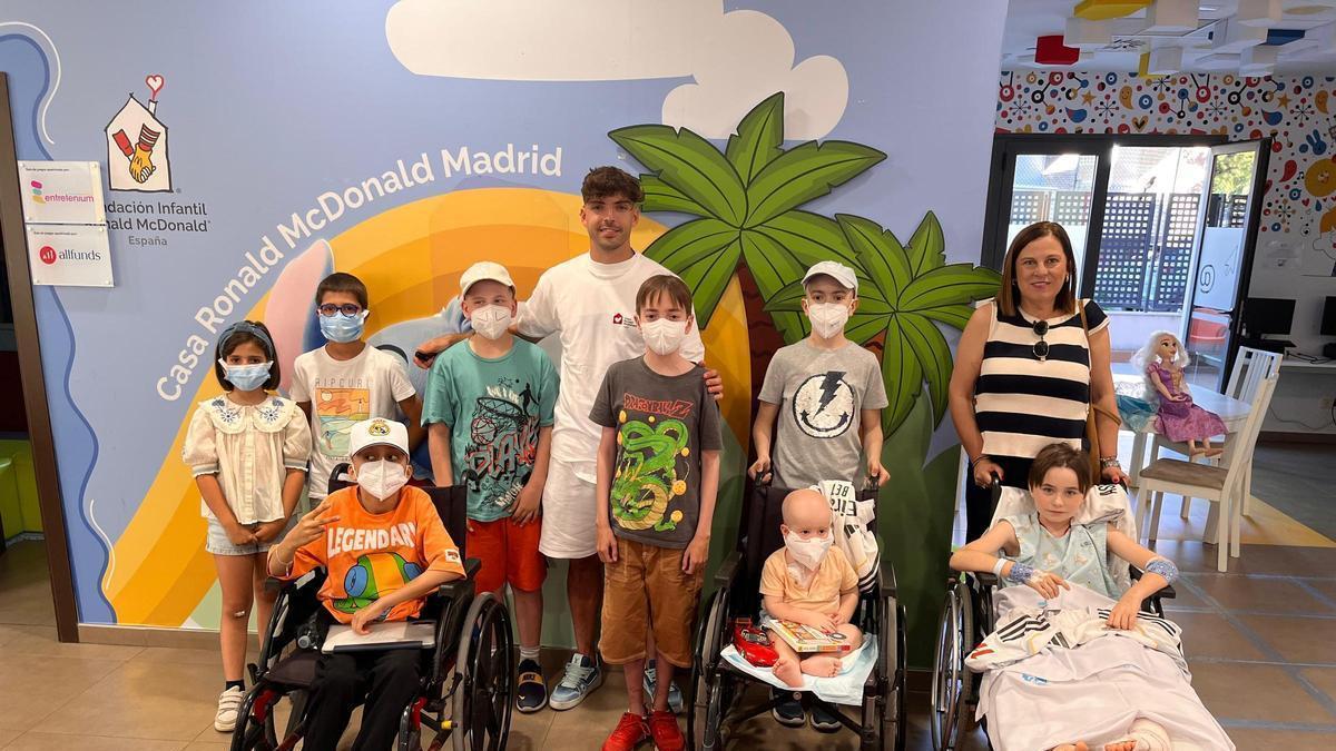 Raúl Asencio posa junto a varios niños y familias en la Casa Ronald de Madrid tras hacer entrega de 40 camisetas firmadas.
