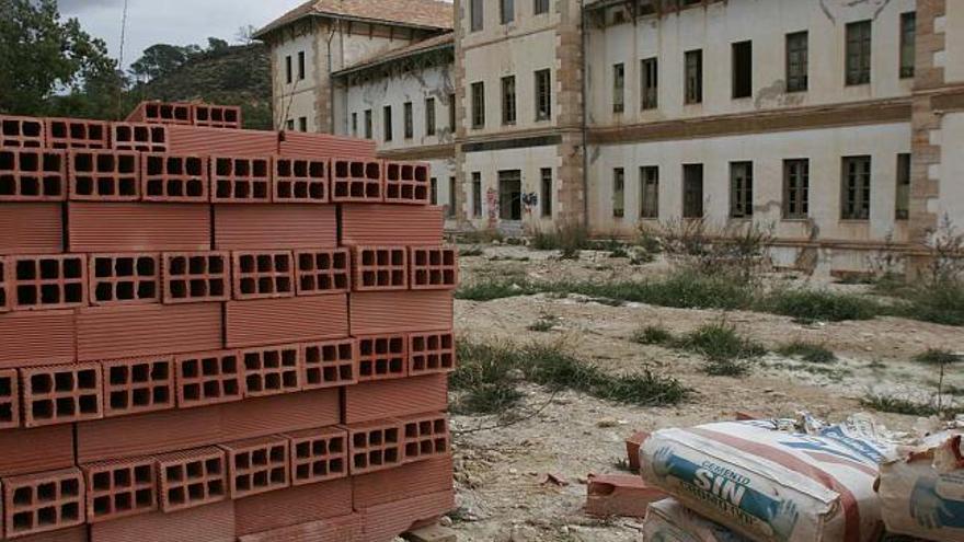 Unos ladrillos apilados aguardan en el suelo junto al edificio del Balneario de Aigües deteriorado por el paso del tiempo