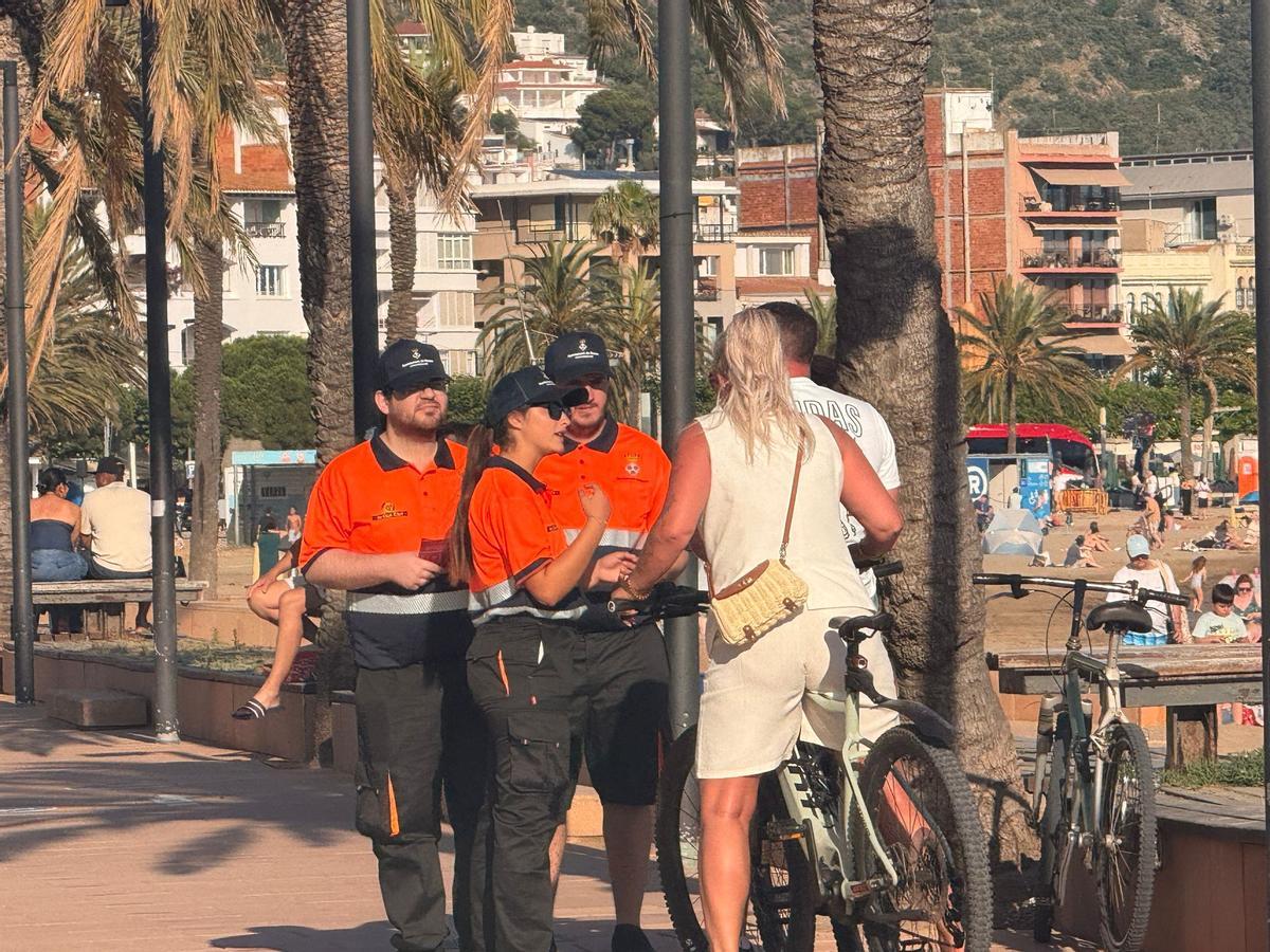Agents cívics informant una parella de turistes sobre la prohibició d'anar en bicicleta pel passeig