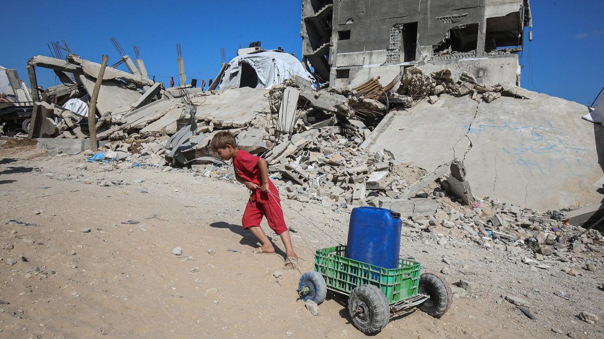 Un niño palestino empuja un bidón de agua en la Franja de Gaza.
