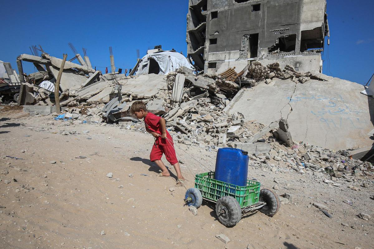 Un niño palestino empuja un bidón de agua en la Franja de Gaza.