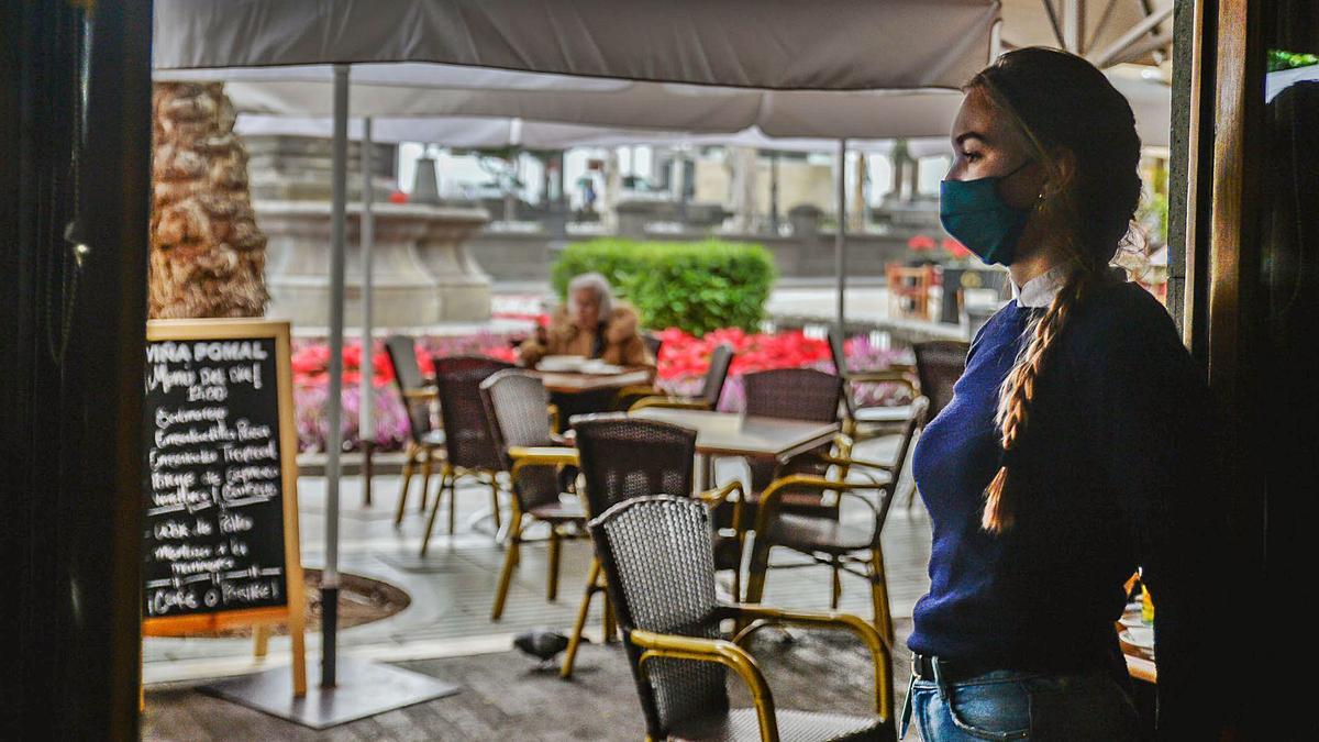 Una camarera aguarda en la puerta de un restaurante ubicado en el casco de la capital grancanaria a que llegue algún cliente. | | JOSÉ CARLOS GUERRA