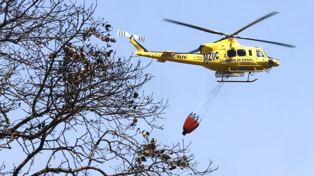Un helicóptero del servicio de extinción de incendios sobrevuela una zona afectada por las llamas en la localidad de Gibraleón, en Huelva.