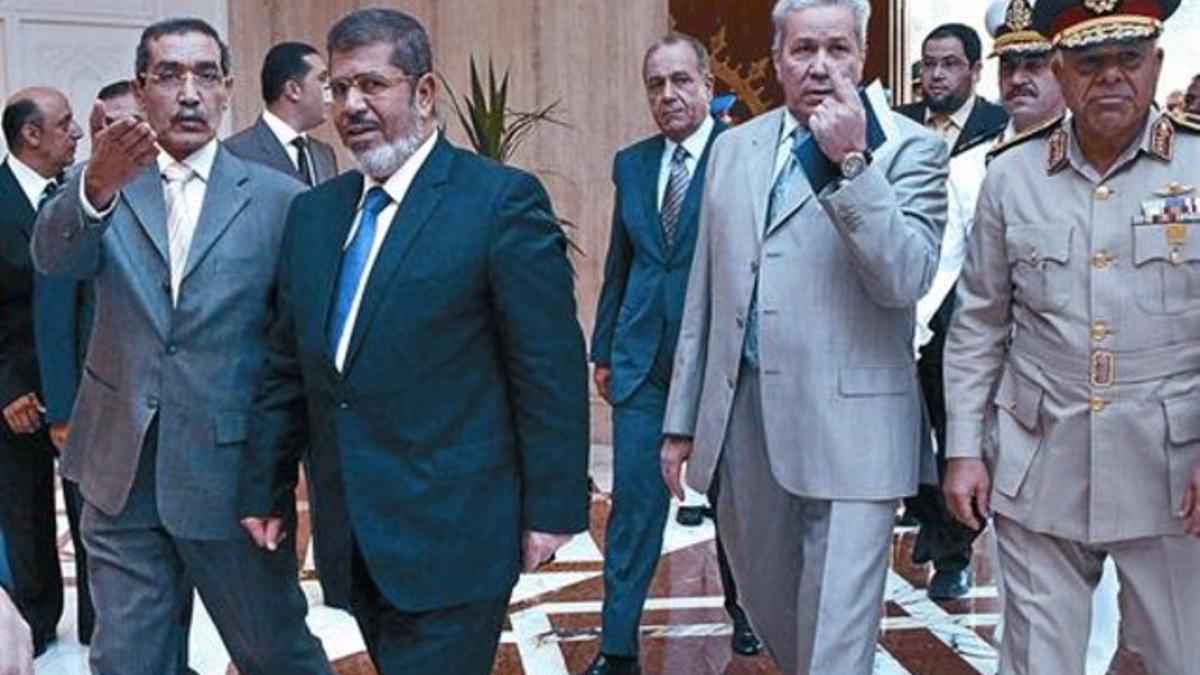 El presidente electo, Mohamed Morsi, se adentra junto a funcionarios y militares en el palacio presidencial egipcio, ayer.