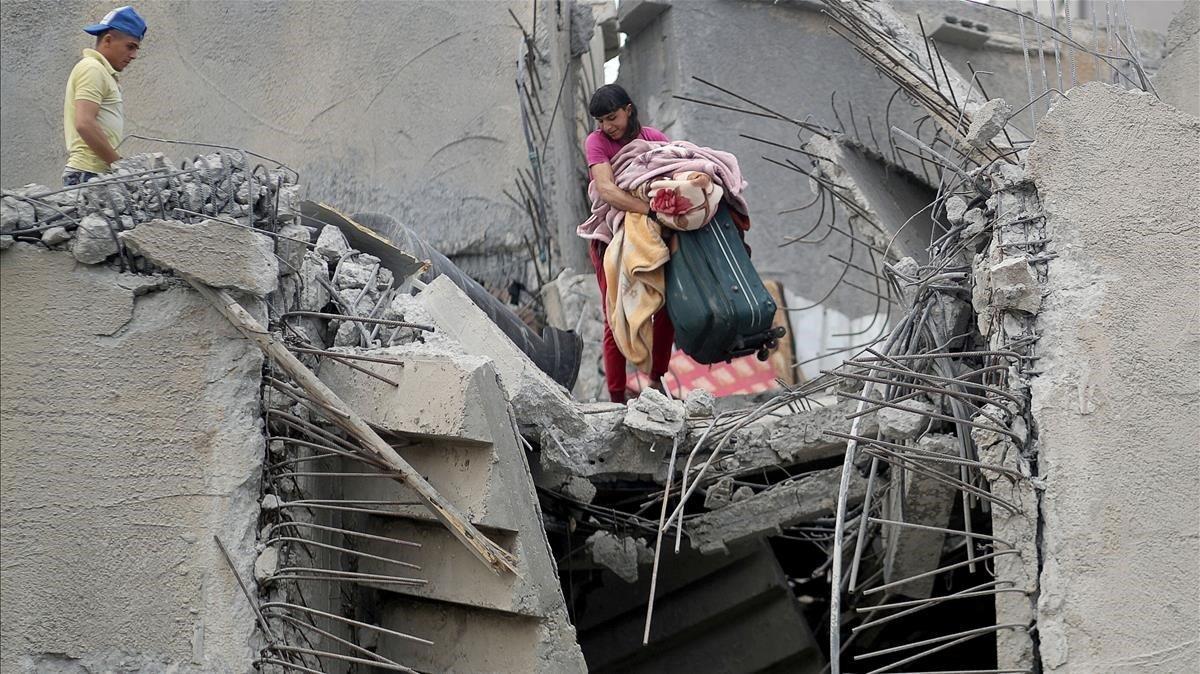 Un palestino recoge sus pertenencias de los escombros de su casa que fue destruida por un ataque aéreo israelí en la ciudad de Gaza.