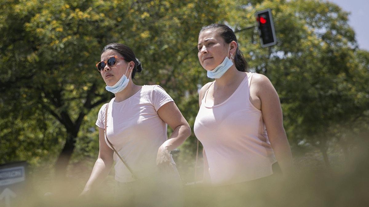 Dos jóvenes pasean con la mascarilla bajada por Sevilla, el pasado 23 de junio