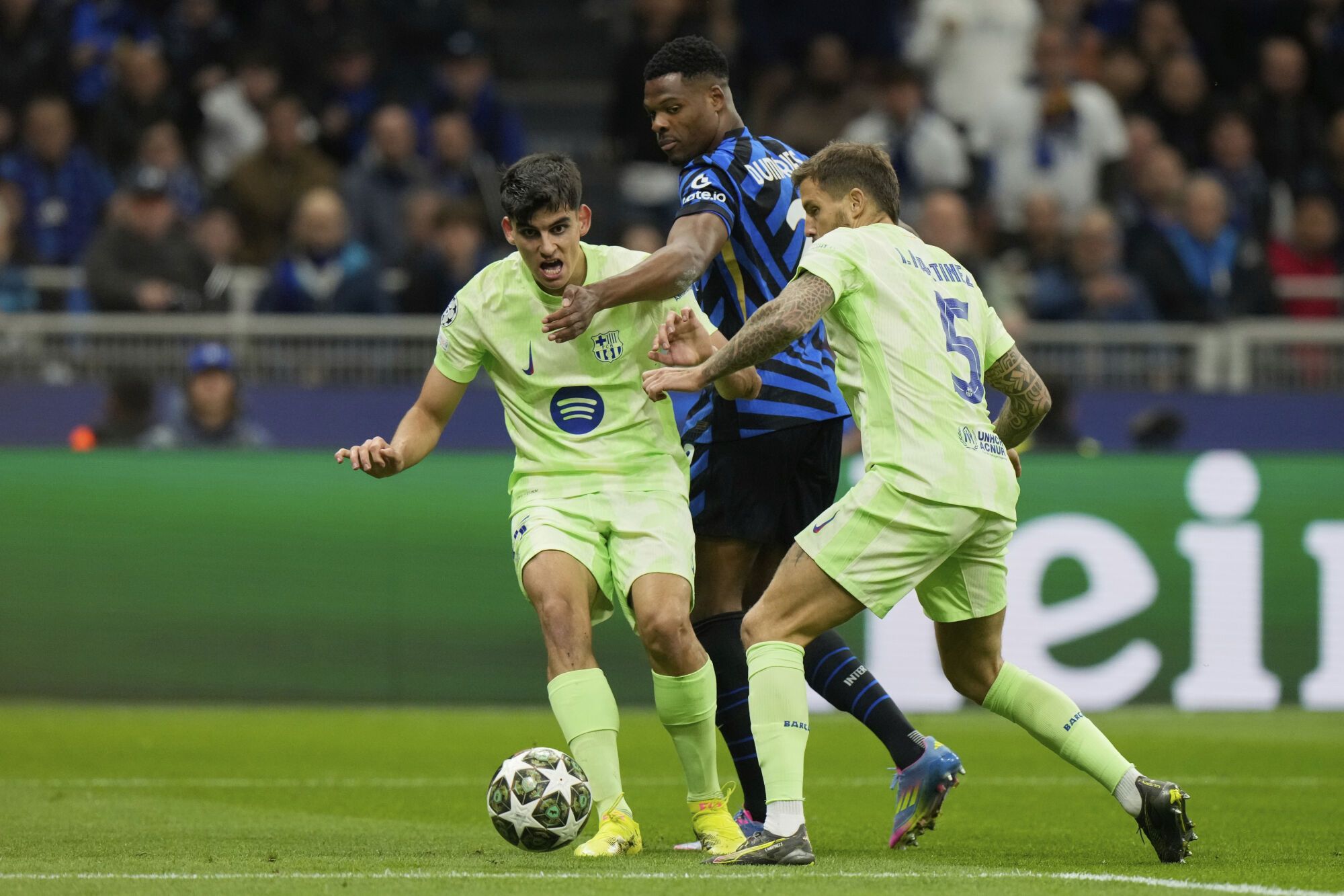 Inter Milan's Denzel Dumfries, center, is challenged by Barcelona's Gerard Martin, left, and Barcelona's Inigo Martinez during the Champions League semifinal second leg soccer match between Inter Milan and Barcelona at San Siro stadium in Milan , Italy, Tuesday, May 6, 2025. (AP Photo/Luca Bruno). EDITORIAL USE ONLY / ONLY ITALY AND SPAIN