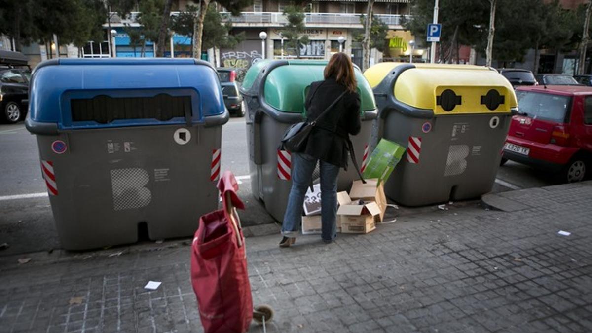 Una mujer deposita residuos en contenedores, en la calle Pujades, en Barcelona.