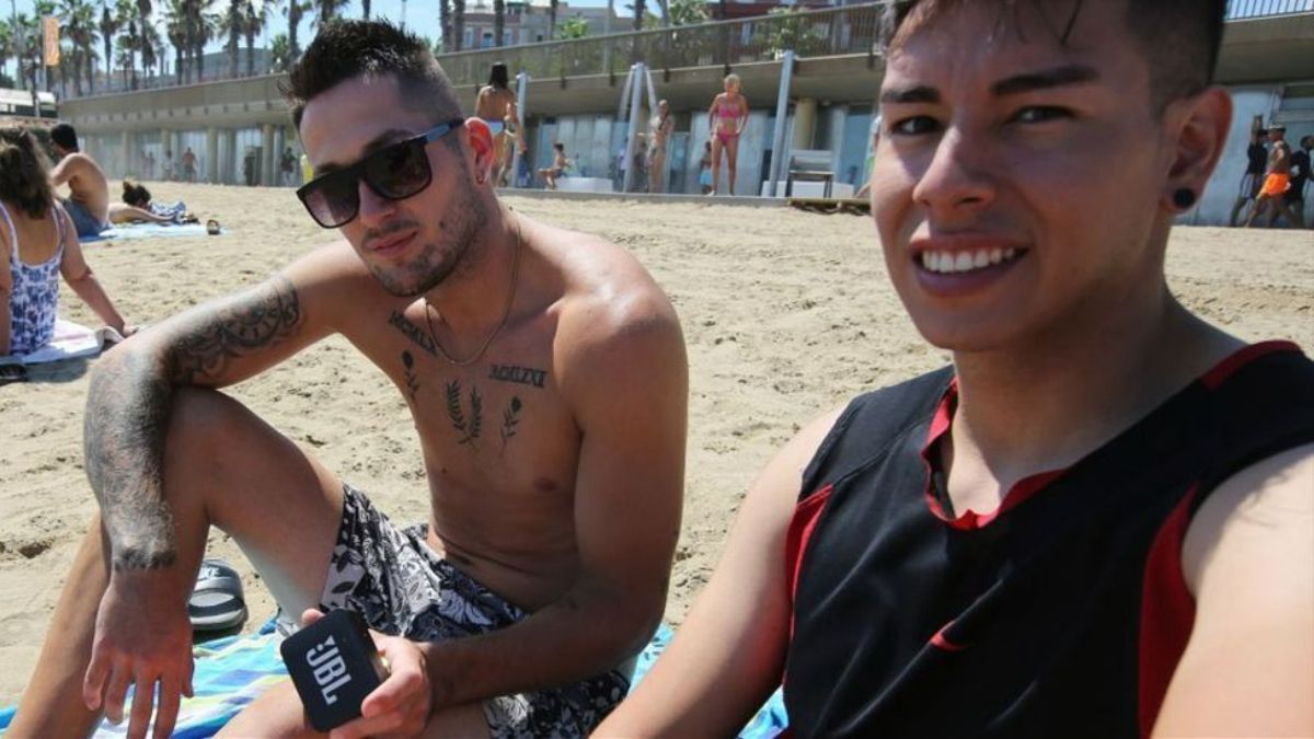 Dos jóvenes escuchan música en la playa con un altavoz inalámbrico, esta semana en Barcelona. Ricard Cugat