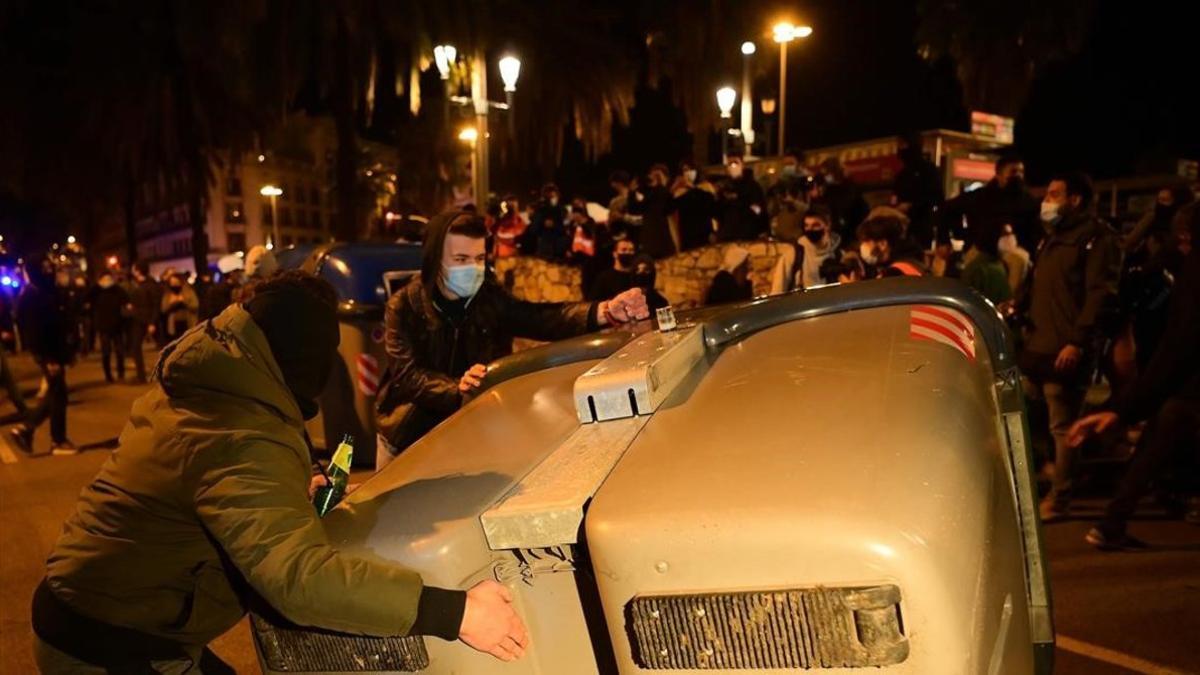 Dos jóvenes arrastran un contenedor cerca del monumento a Colón, en Barcelona.