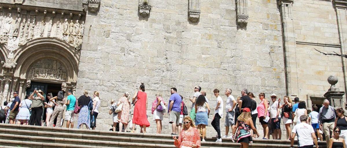 Pese al intenso calor, turistas y peregrinos aguardan para acceder a la Catedral de Santiago / J. PRIETO